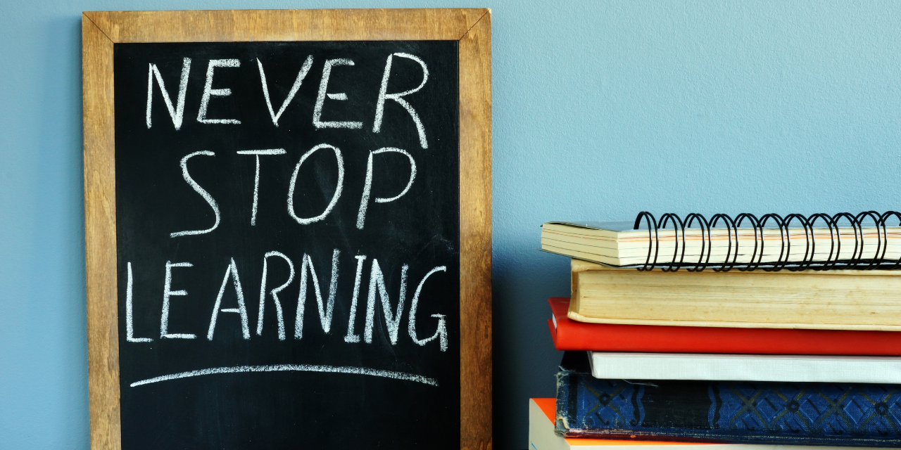 Blackboard with sign Never stop learning and books.