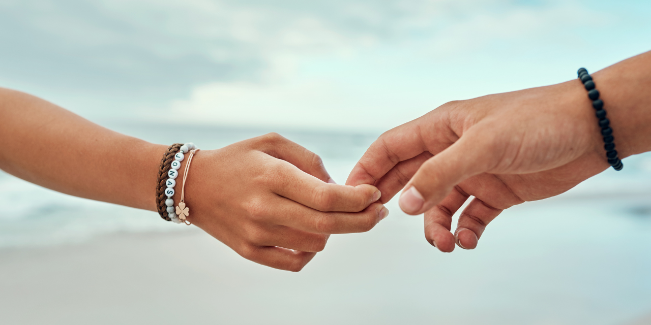 two people on the beach letting go of each others hands