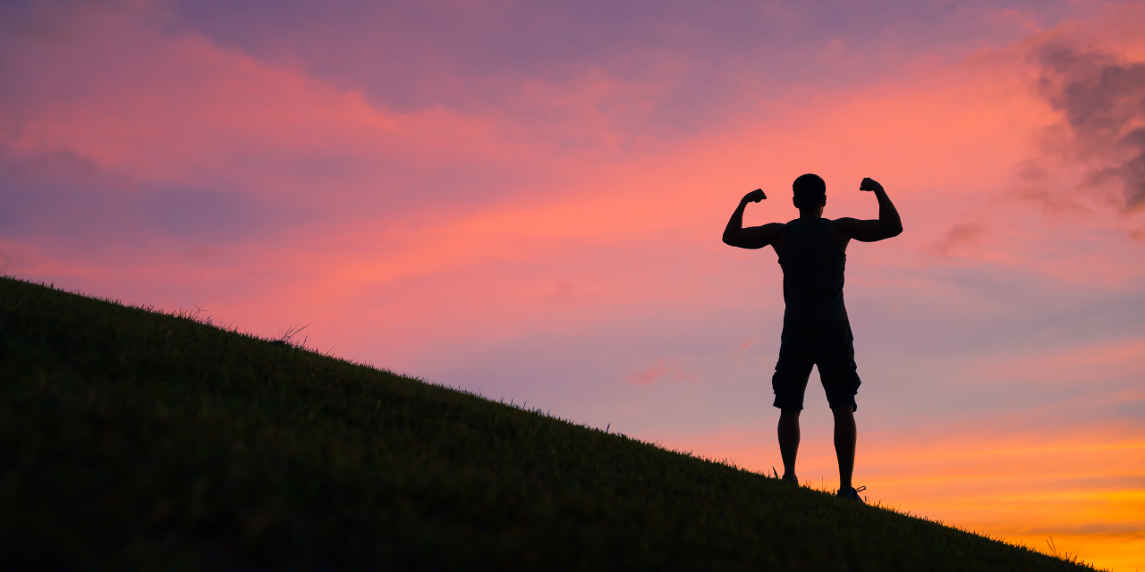 Man flexing muscles while looking at sunset