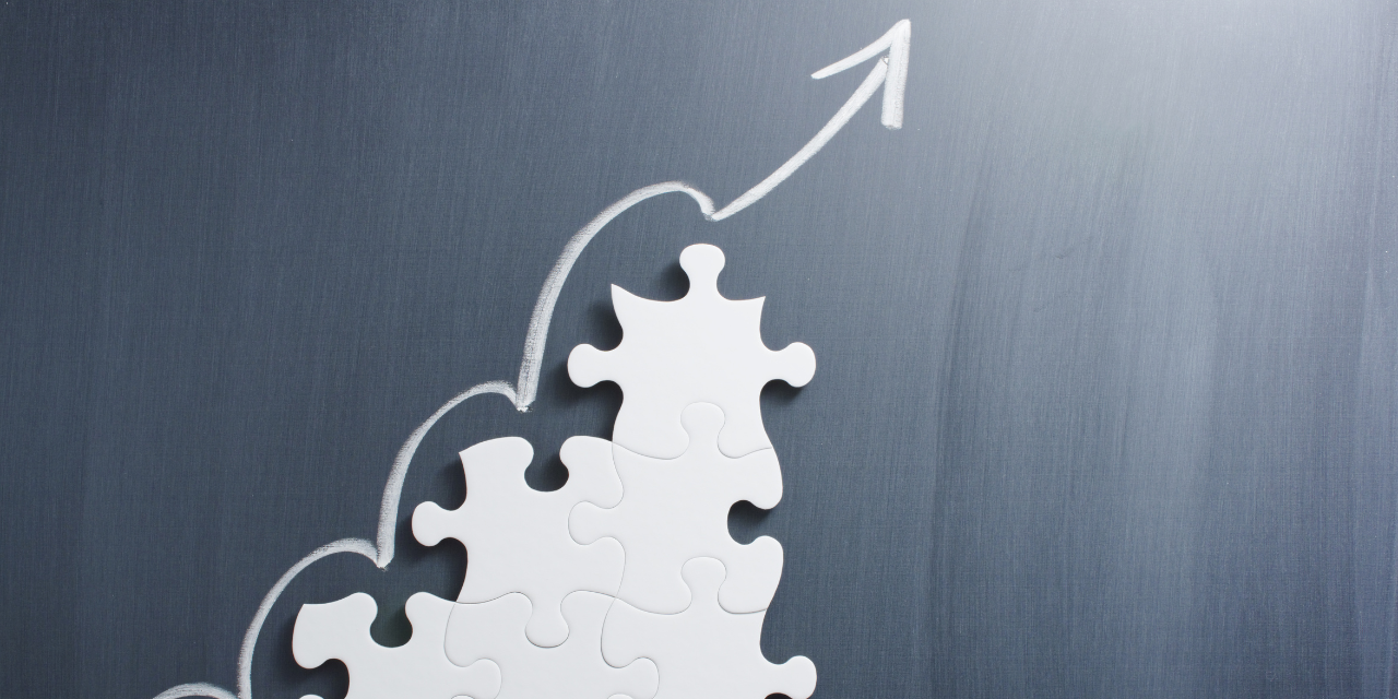 Steps shaped jigsaw puzzle and up arrow on blackboard.